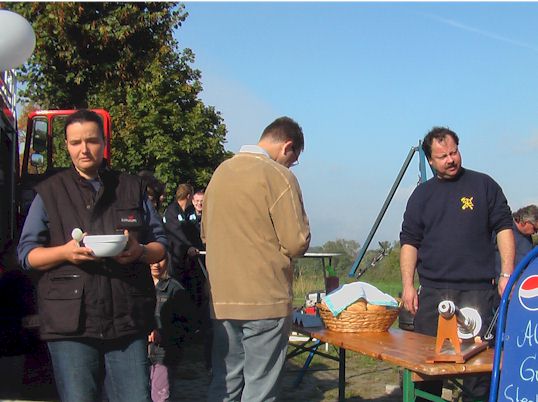Besucher mit Suppensch&uuml;ssel vor dem Grillstand